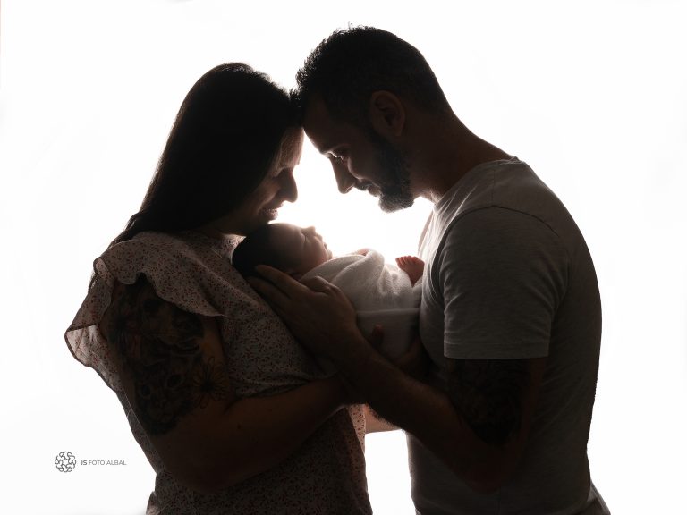 bebe recien nacido en brazos de sus padres durante su sesion de fotografía new born