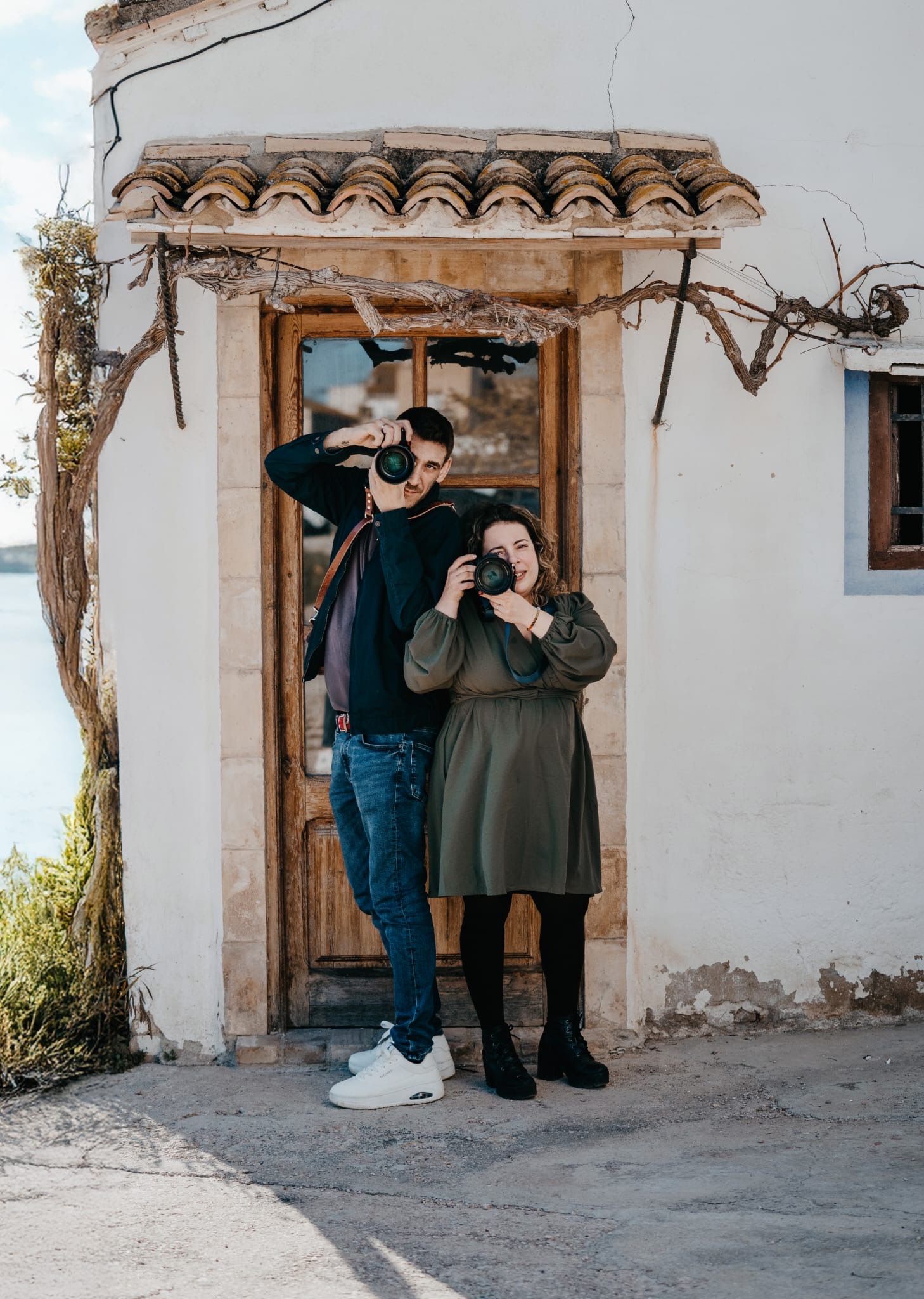 Pareja de fotógrafos sonriendo entre flores de almendro, retrato natural de Sheila y Juanvi de JS Foto Albal, estudio fotográfico en Albal (Valencia).